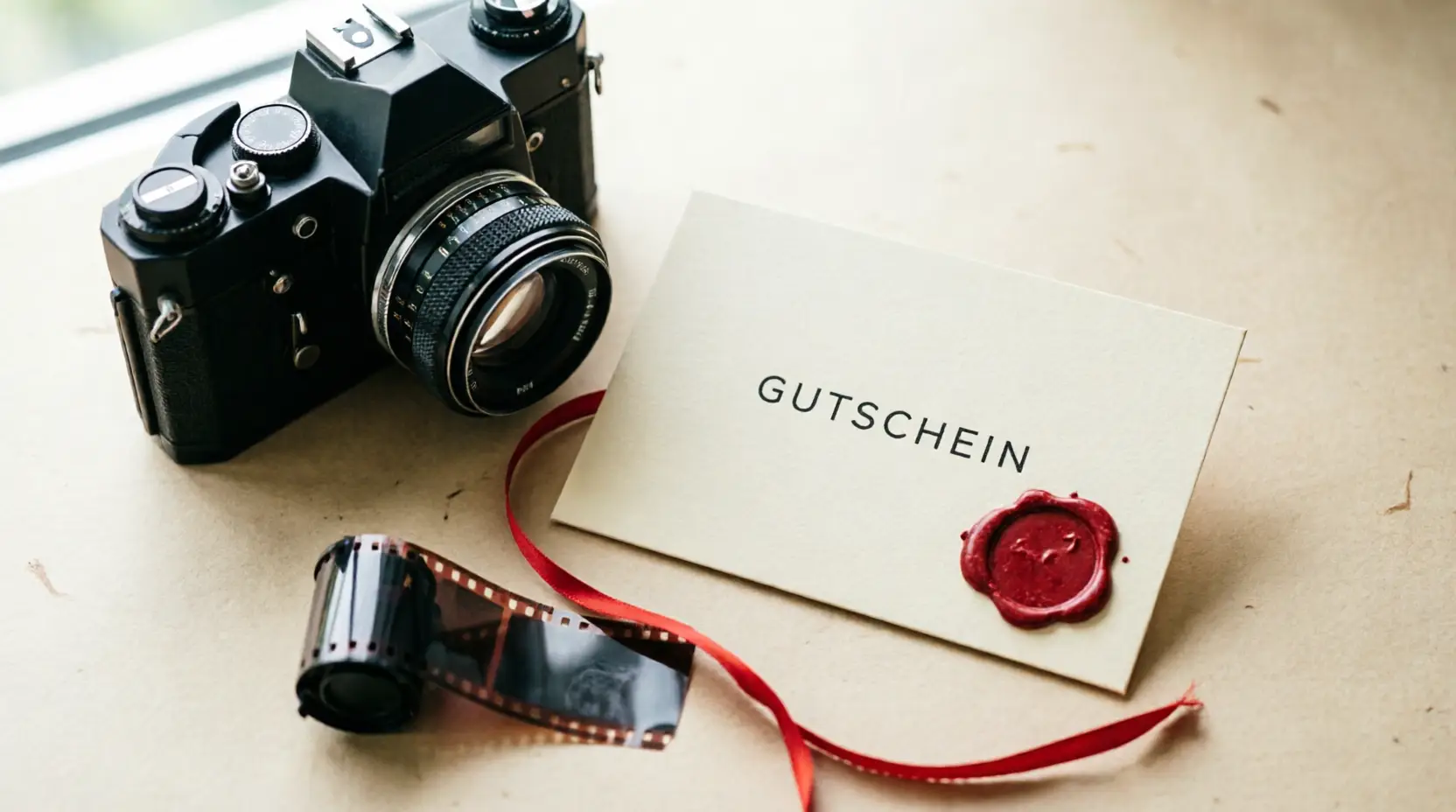 Liebevoll verpackter Geschenkgutschein neben einer Kamera